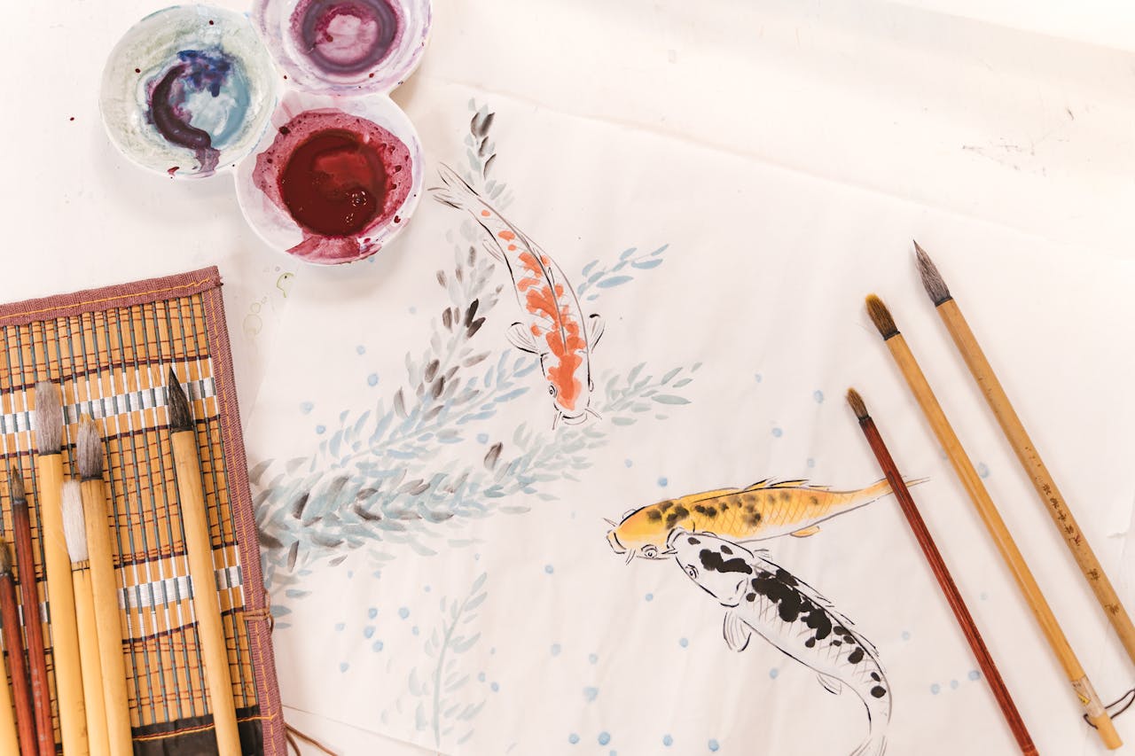 Artistic koi fish painting surrounded by brushes and paint palette, showcasing creativity.