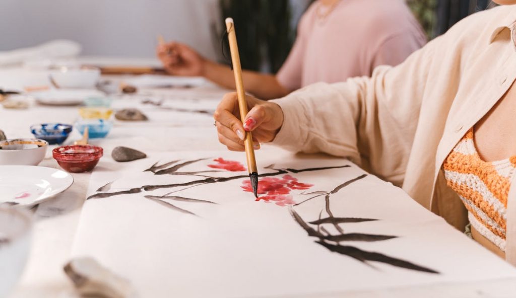 Close-up of a woman painting with a brush in an art class, focusing on creativity and technique.